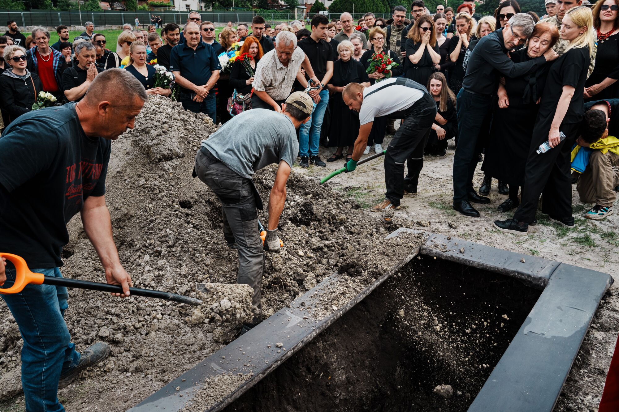 Mezarlık çalışanları, askeri bir cenaze töreni sırasında bir mezarı toprakla dolduruyor 