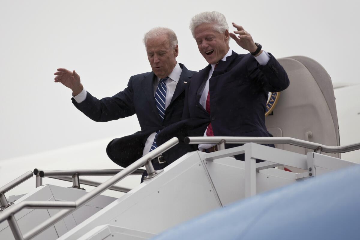 Joe Biden and Bill Clinton wave to onlookers as they exit a plaine