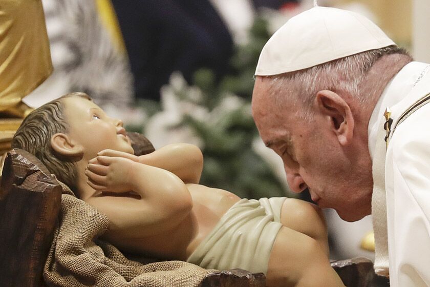 Pope Francis kisses a statue of Baby Jesus as he celebrates Christmas Eve Mass in St. Peter's Basilica in Vatican City on Tuesday.
