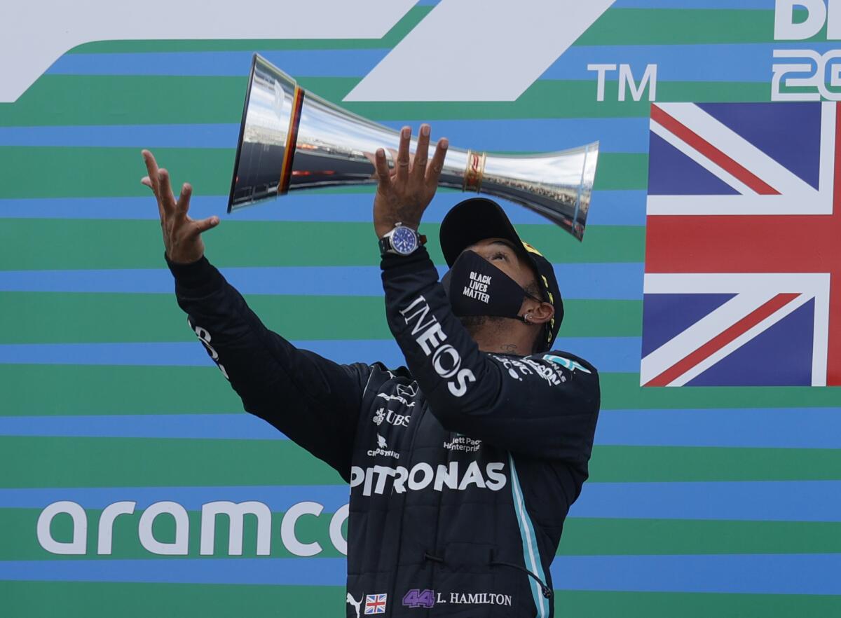 Lewis Hamilton throws the trophy in the air at the podium.