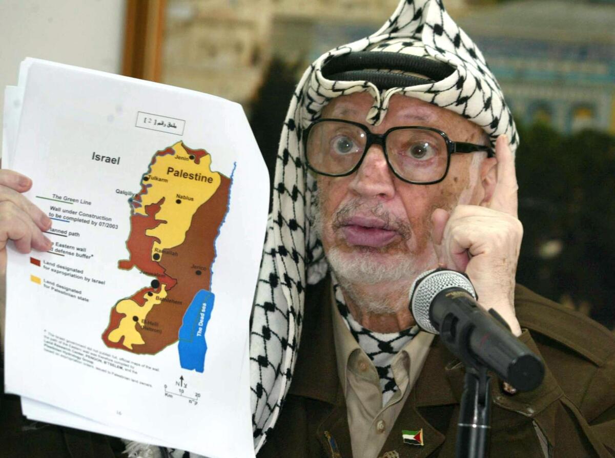 Palestinian leader Yasser Arafat in 2003, discussing the controversial Israeli "security" fence during a meeting with a French delegation in the West Bank city of Ramallah. Arafat died in 2004 after a sudden deterioration in his health.