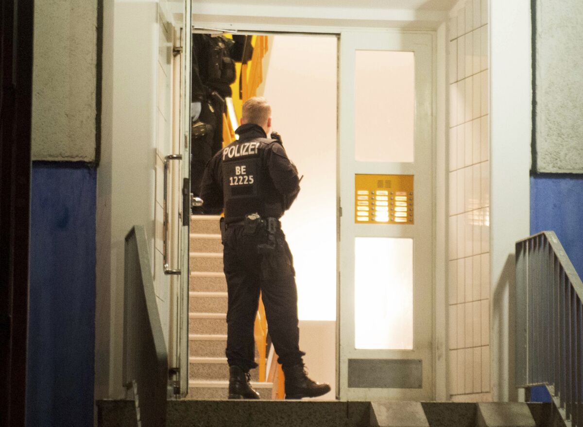 Police forces are standing in the hallway of an apartment building in Marzahn-Hellersdorf, Germany, Tuesday, Jan.14, 2020. In the early morning, investigators swarmed out in several federal states. The reason for the searches is the suspicion of preparation of a serious act of violence that endangers the state. (Dennis Brätsch/dpa via AP)