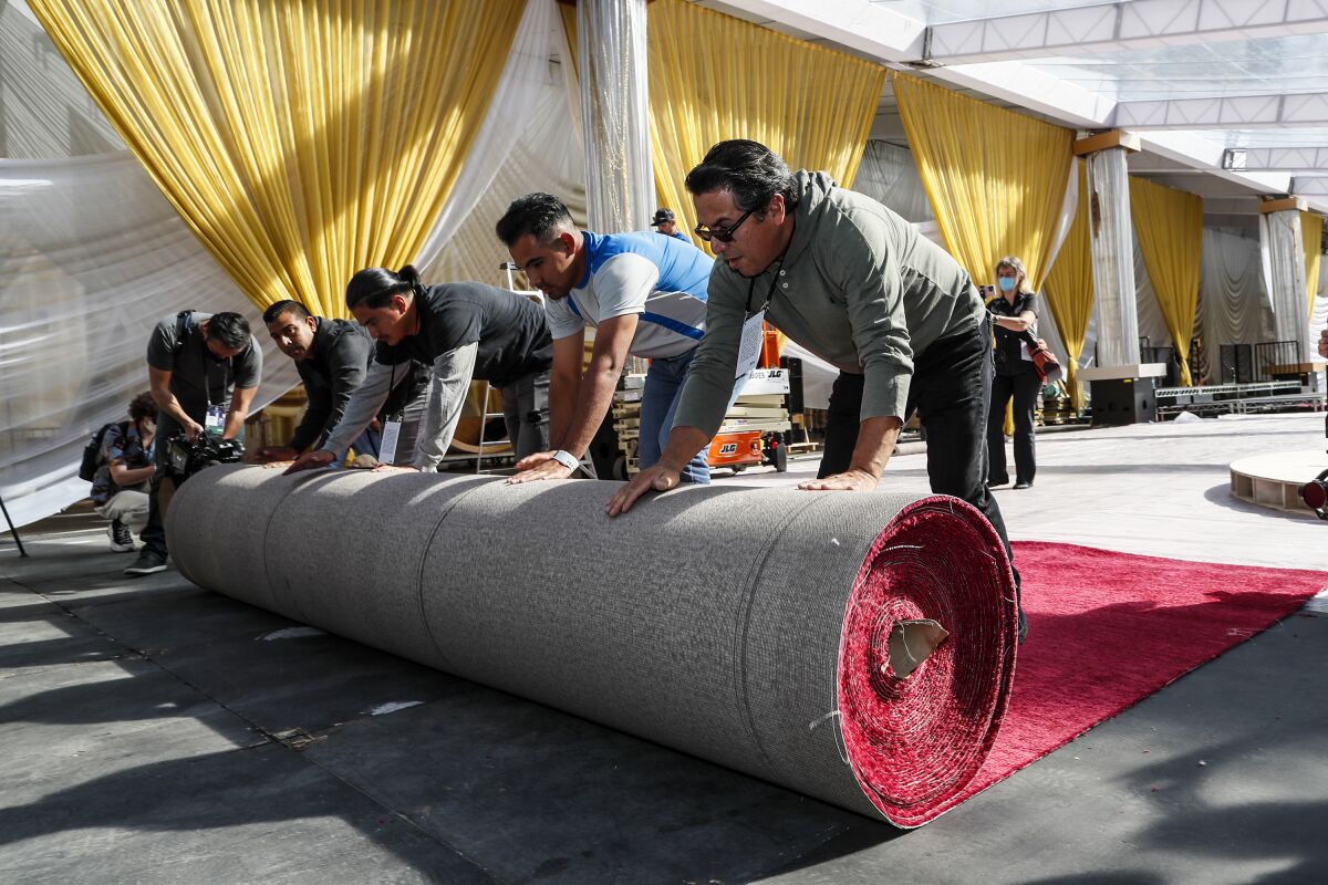 a group of men unroll a red carpet