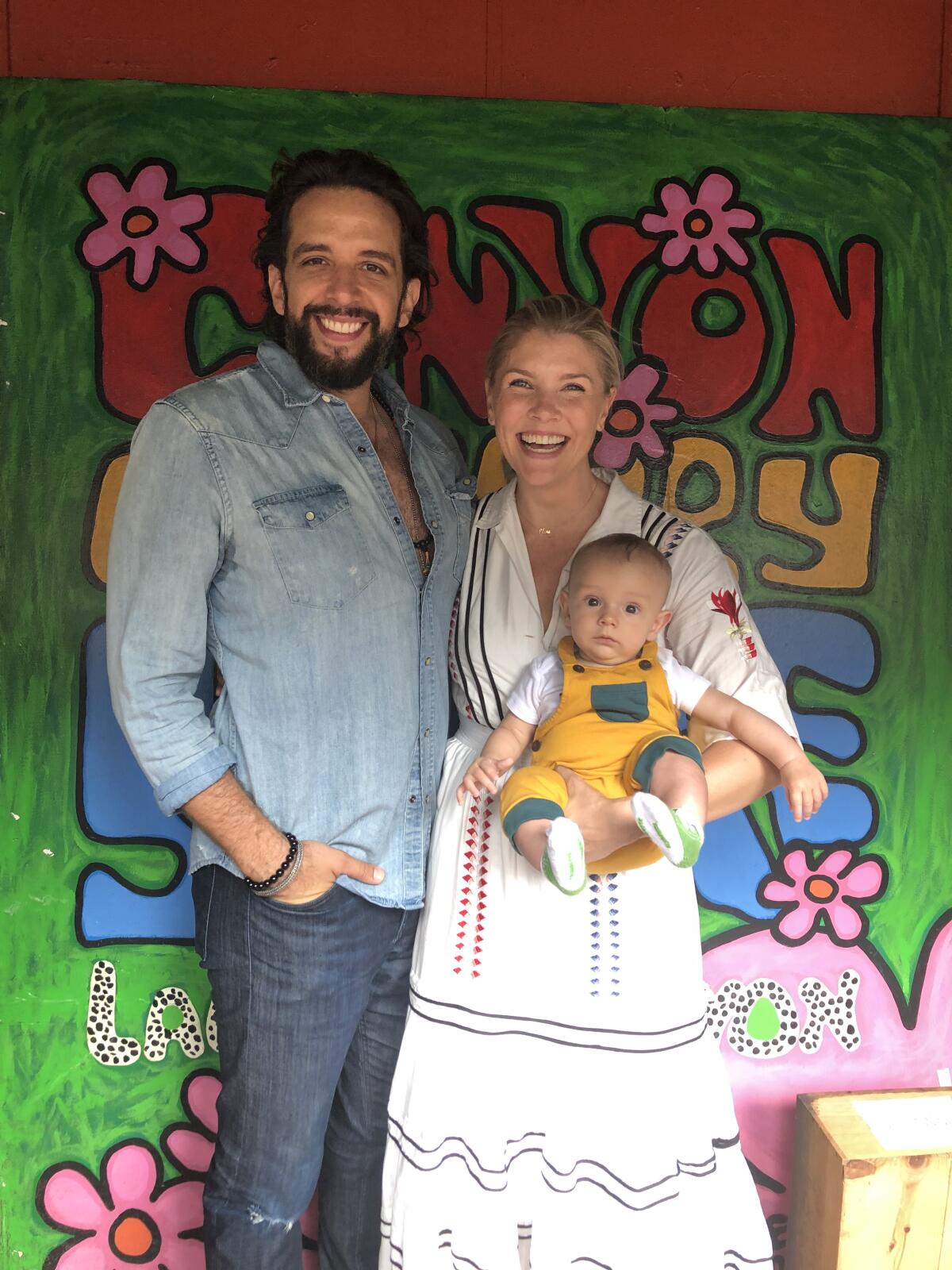 A man posing with a woman holding a baby