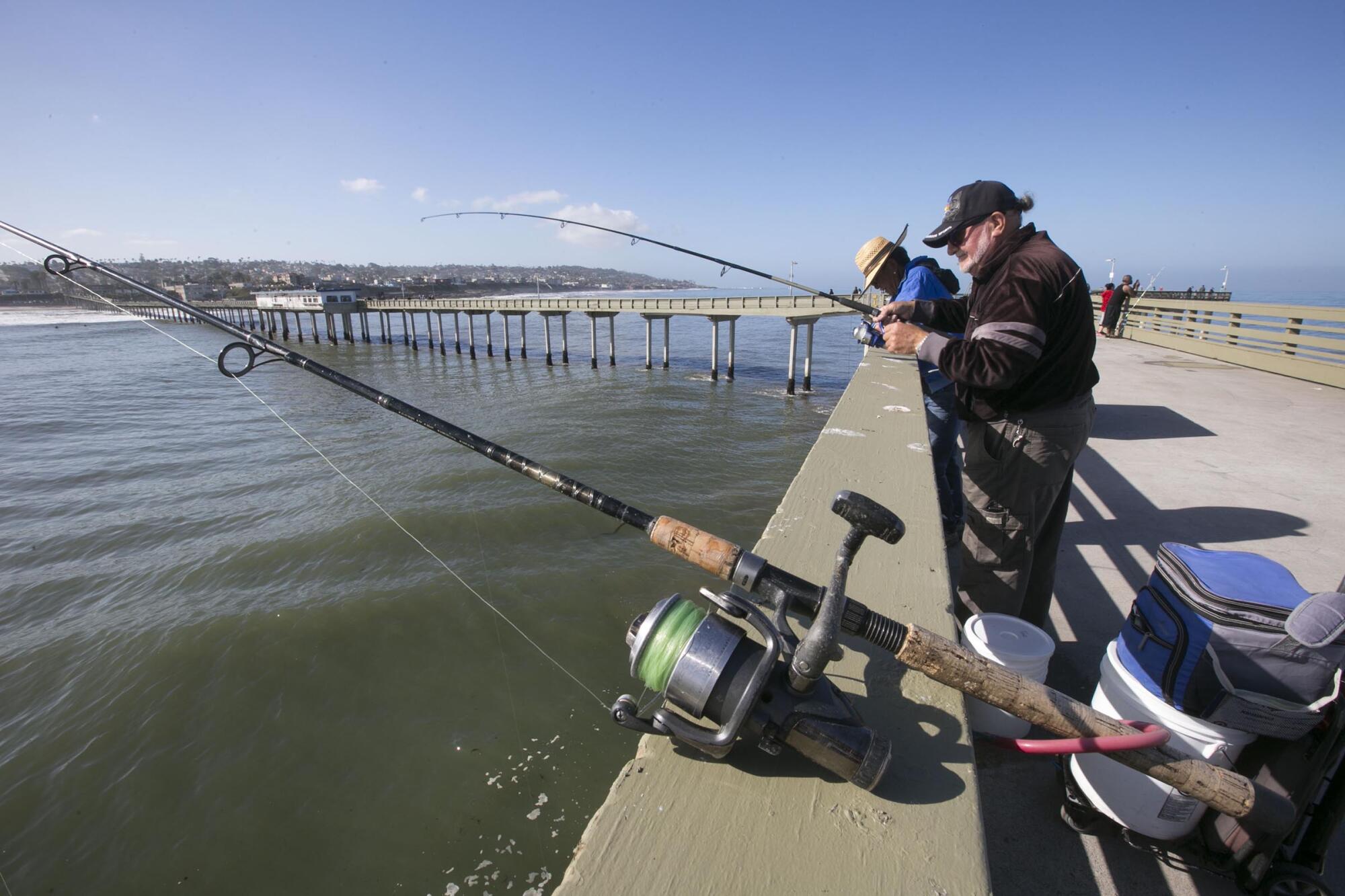 Tom Garland, 57, casts out three lines on the first day of the reopening of the Ocean Beach Pier 