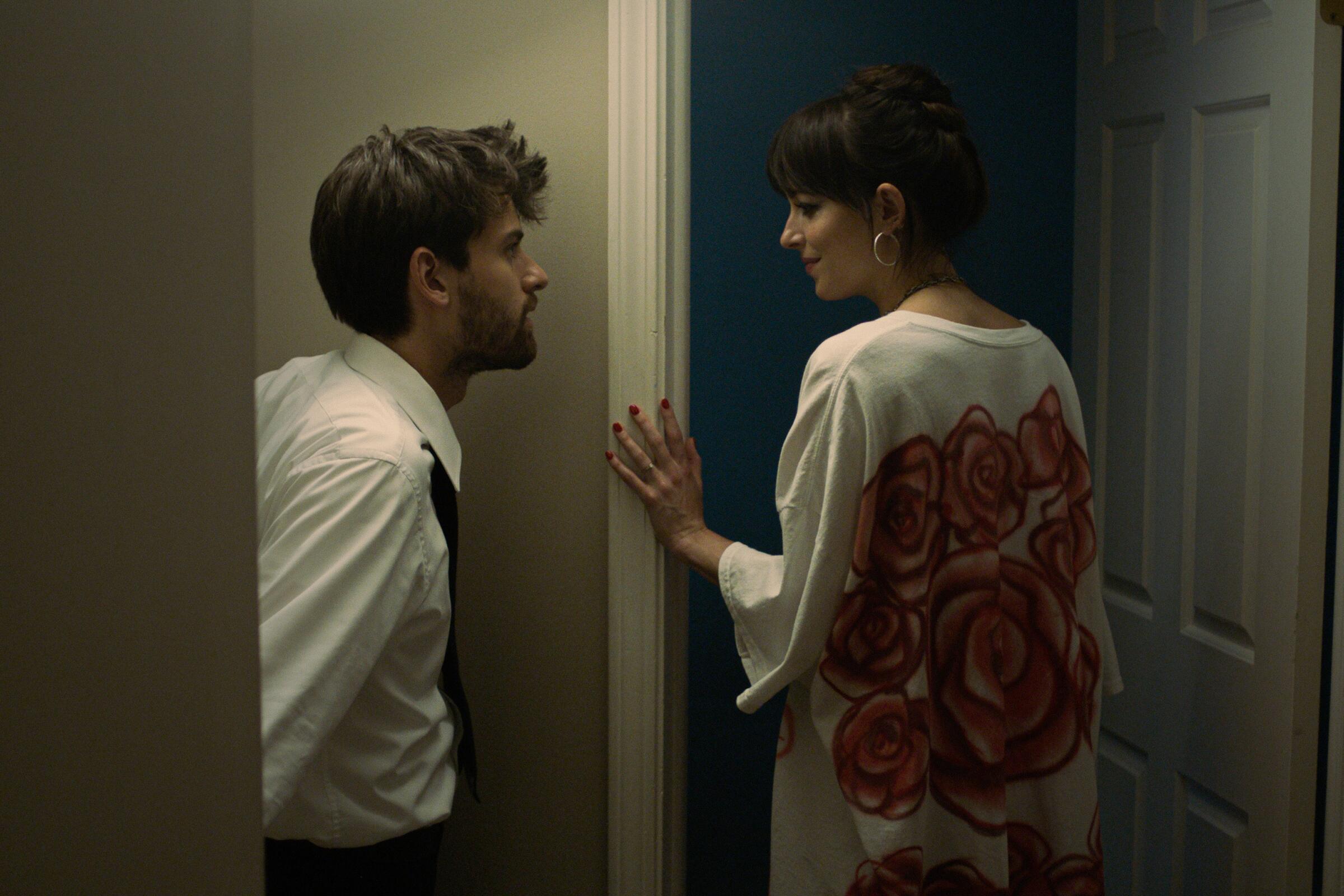 A man talks to a woman while she enters a doorway