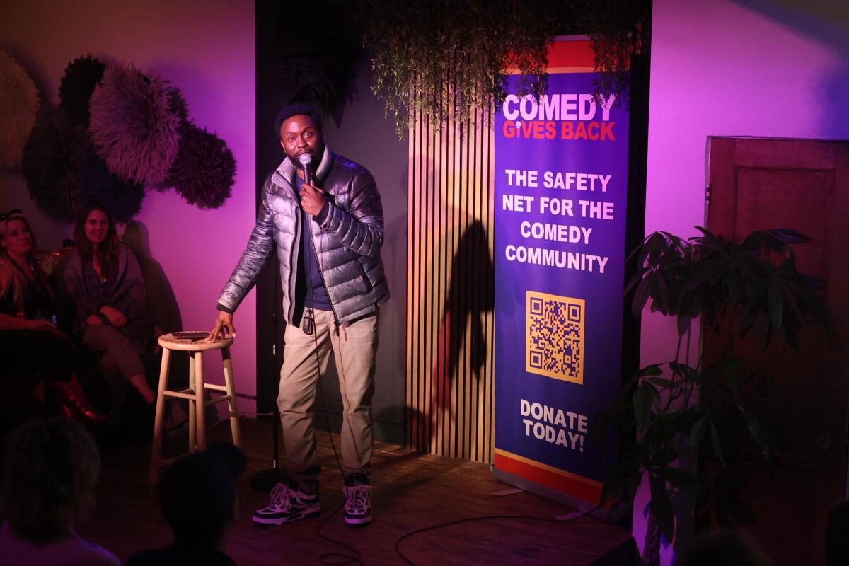comedian with a stool and a microphone telling jokes to a crowd.