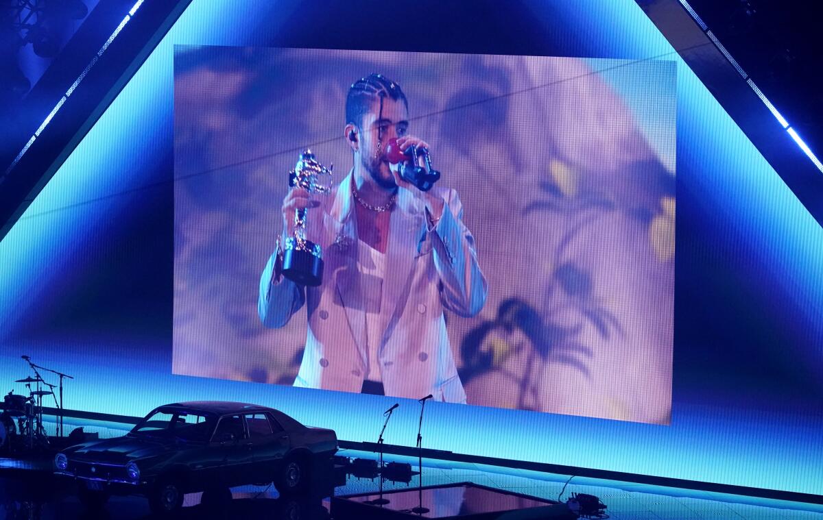 Bad Bunny is seen accepting an award in an image projected on a screen