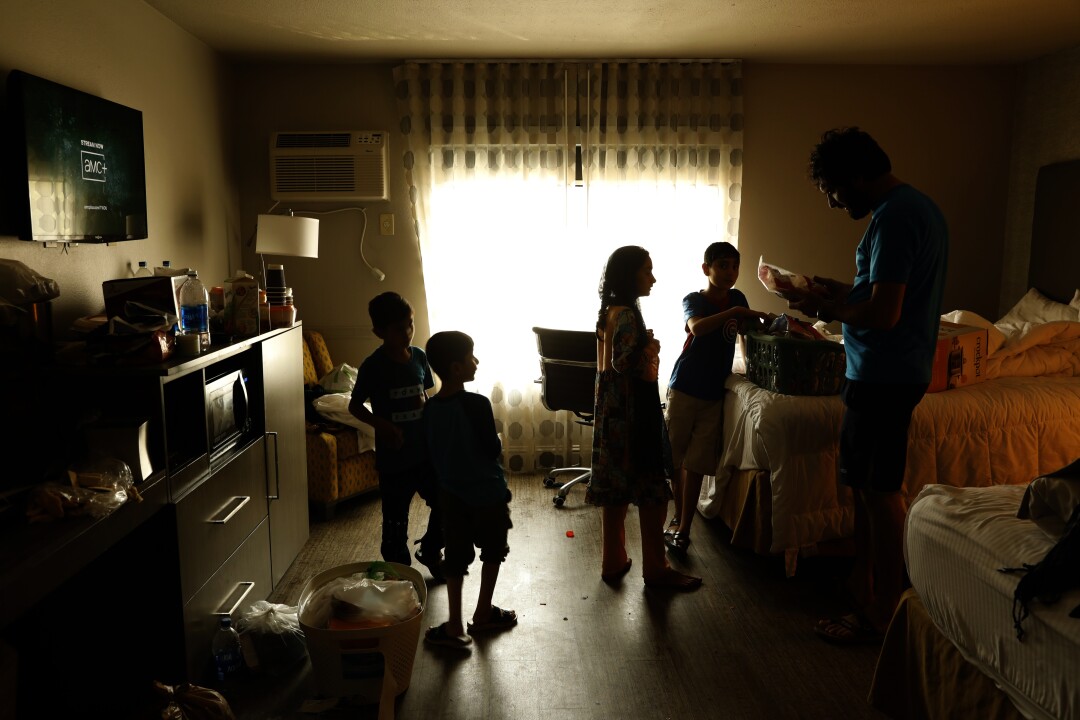 A family is seen in silhouette inside their temporary residence