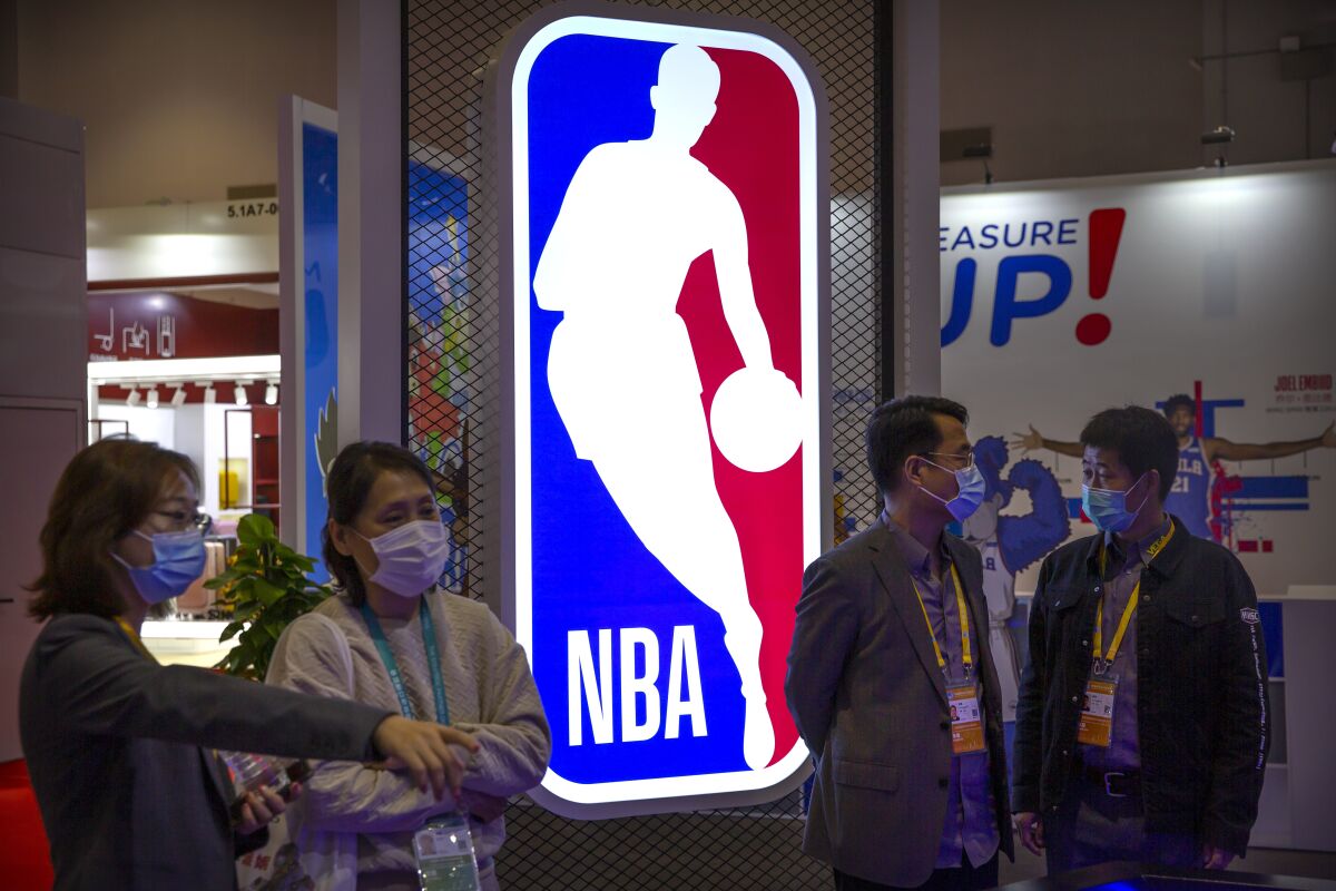 Visitors wearing face masks to protect against the coronavirus look at a display from the National Basketball Association (NBA) at the China International Import Expo in Shanghai, Thursday, Nov. 5, 2020. The expo, one of China's largest annual trade fairs, kicked off on Thursday as the ongoing COVID-19 pandemic has largely been controlled within China. (AP Photo/Mark Schiefelbein)