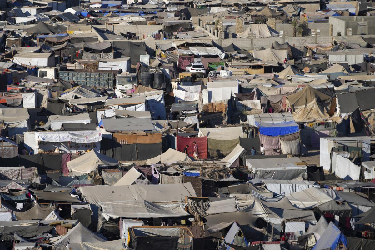 Tents are crammed together  on a beach 