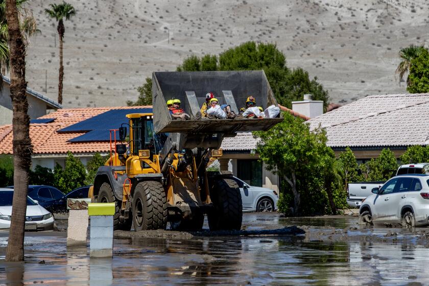 CATHEDRAL CITY, CA - AUGUST 21, 2023: Residents from a senior living facility are held by firefighters in a front loader while being brought to safety after the Affinity Senior Living was inundated with flood waters from tropical storm Hilary on August 21, 2023 in Cathedral City, California. (Gina Ferazzi / Los Angeles Times)