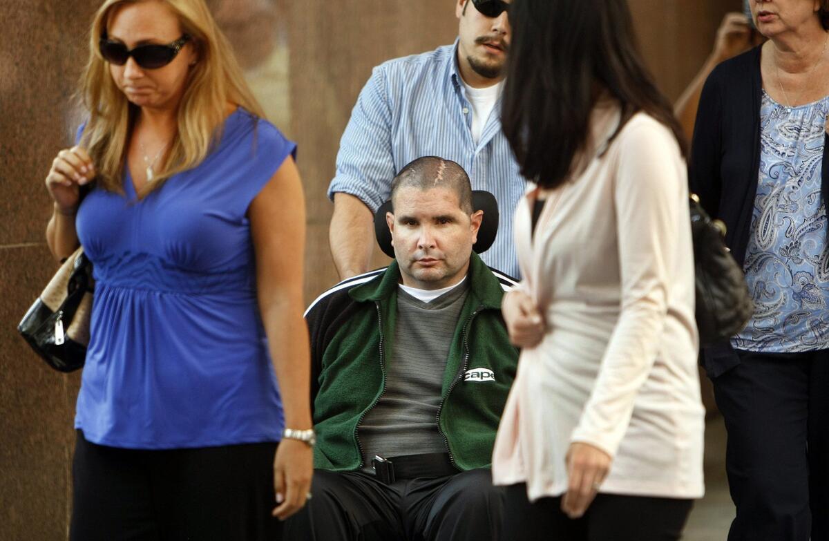 Bryan Stow. in a wheelchair and assisted by a caregiver, is surrounded by family members as he leaves the Los Angeles County Superior Courthouse last month. A witness said Monday that his medical bills and lost wages could total $37 million.