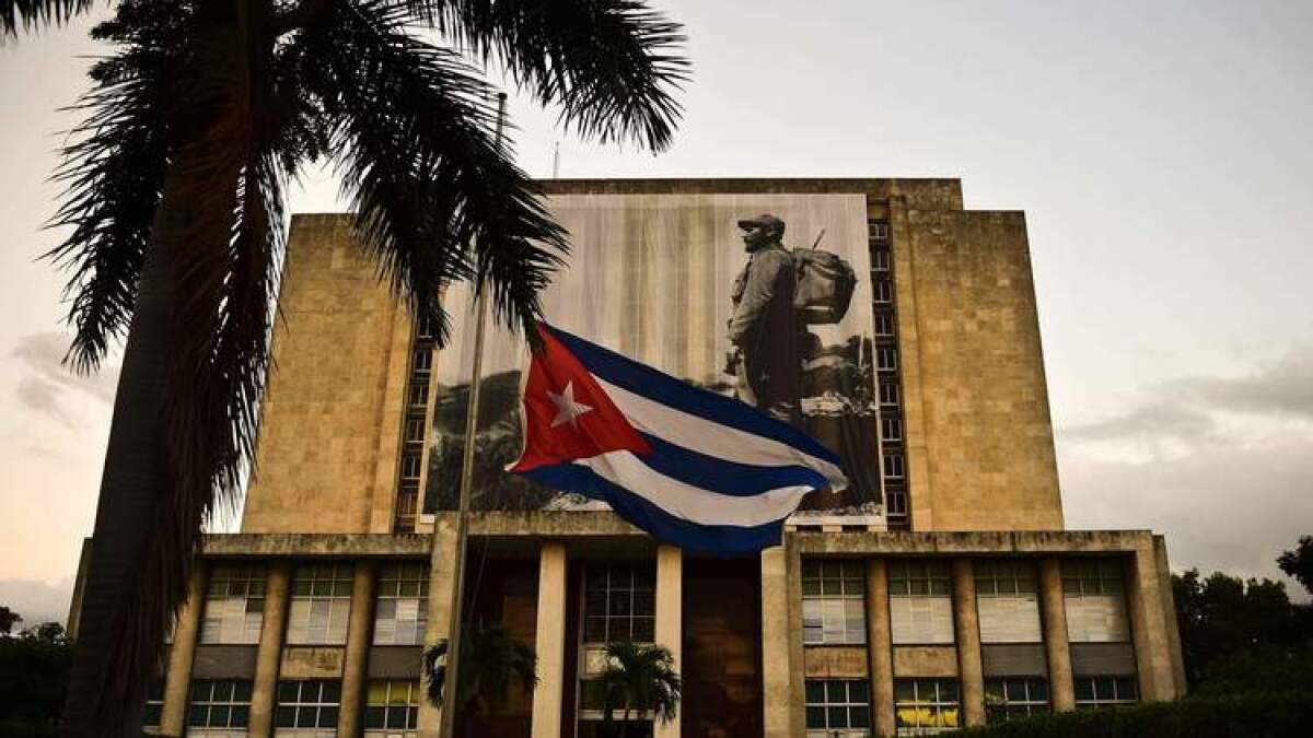 The Cuban flag hangs at half-staff in front of a picture of Fidel Castro on the facade of the Cuban national library in Havana.