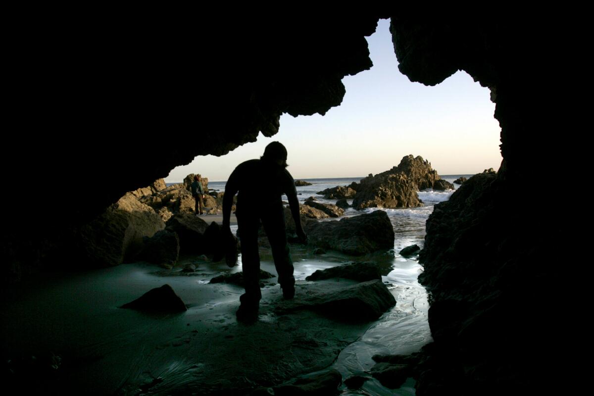 Greg Wood 25, of Northridge enters a cave on the beach at Leo Carillo State Park in Malibu which offers camping and beach access.