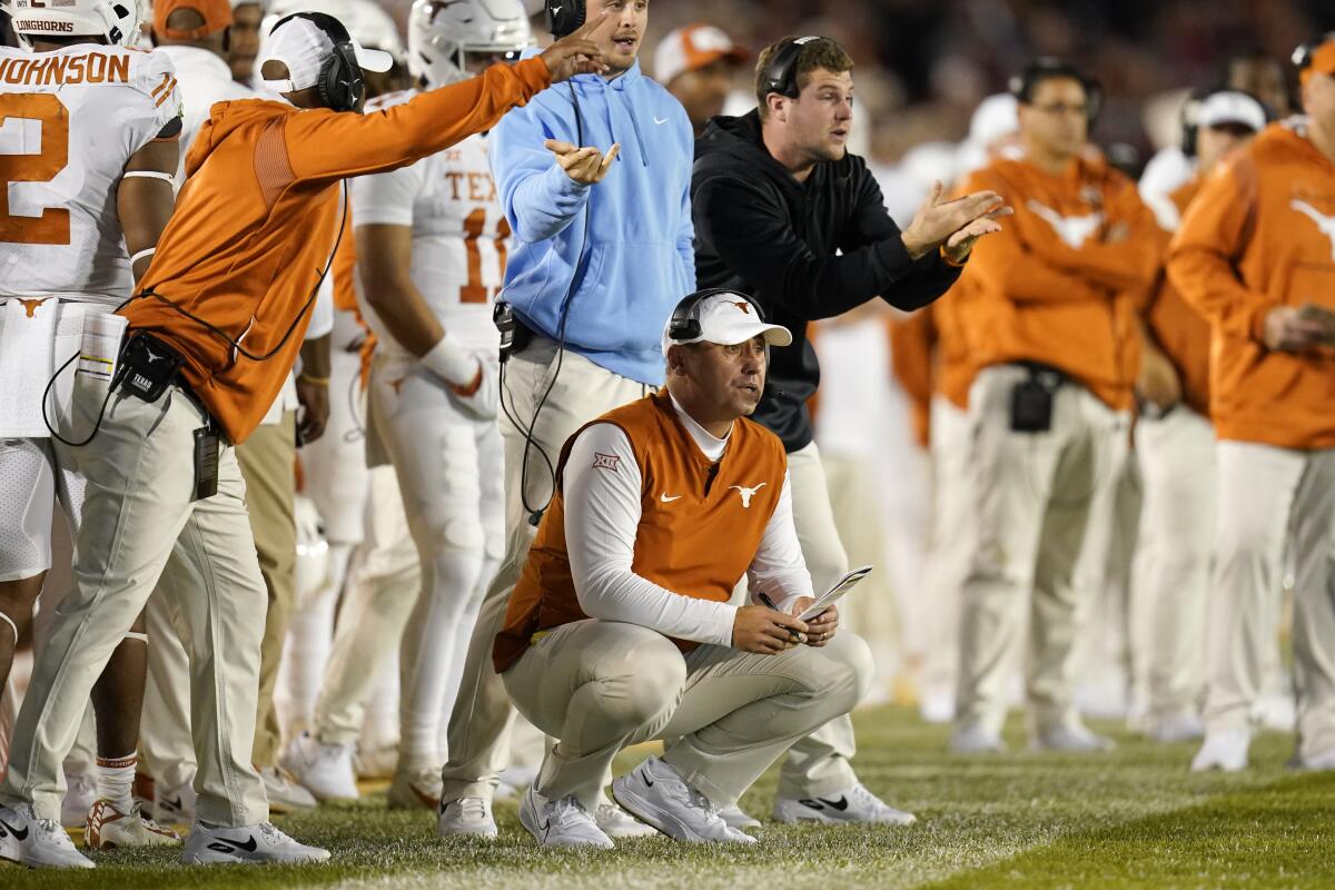 Texas coach Steve Sarkisian, center, crouches down and watches his team from the sideline 