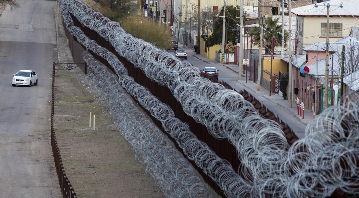 Coils of concertina wire hang from the border fence alongside International Street in Nogales, Ariz.