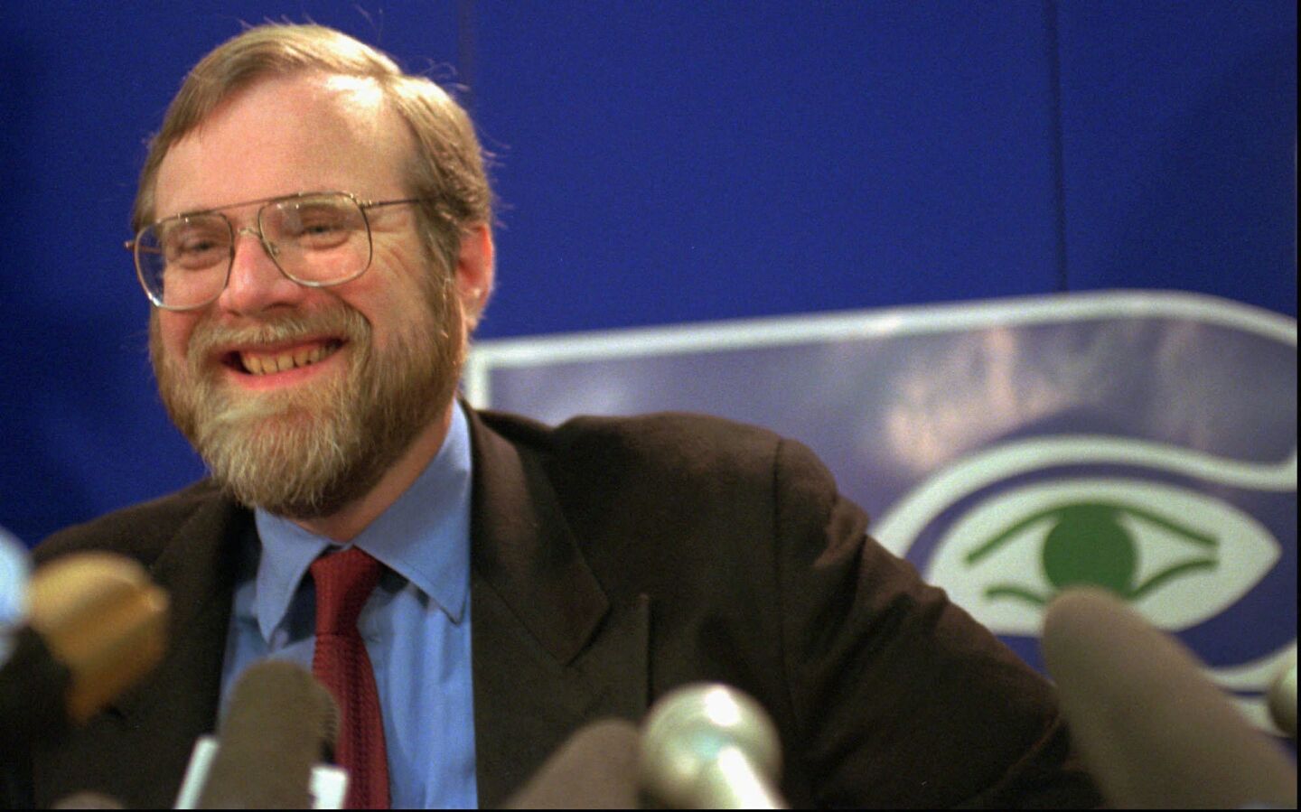 Paul Allen at Seattle Seahawks headquarters in Kirkland, Wash., on April 23, 1996. The eye of the team logo peers over his shoulder.