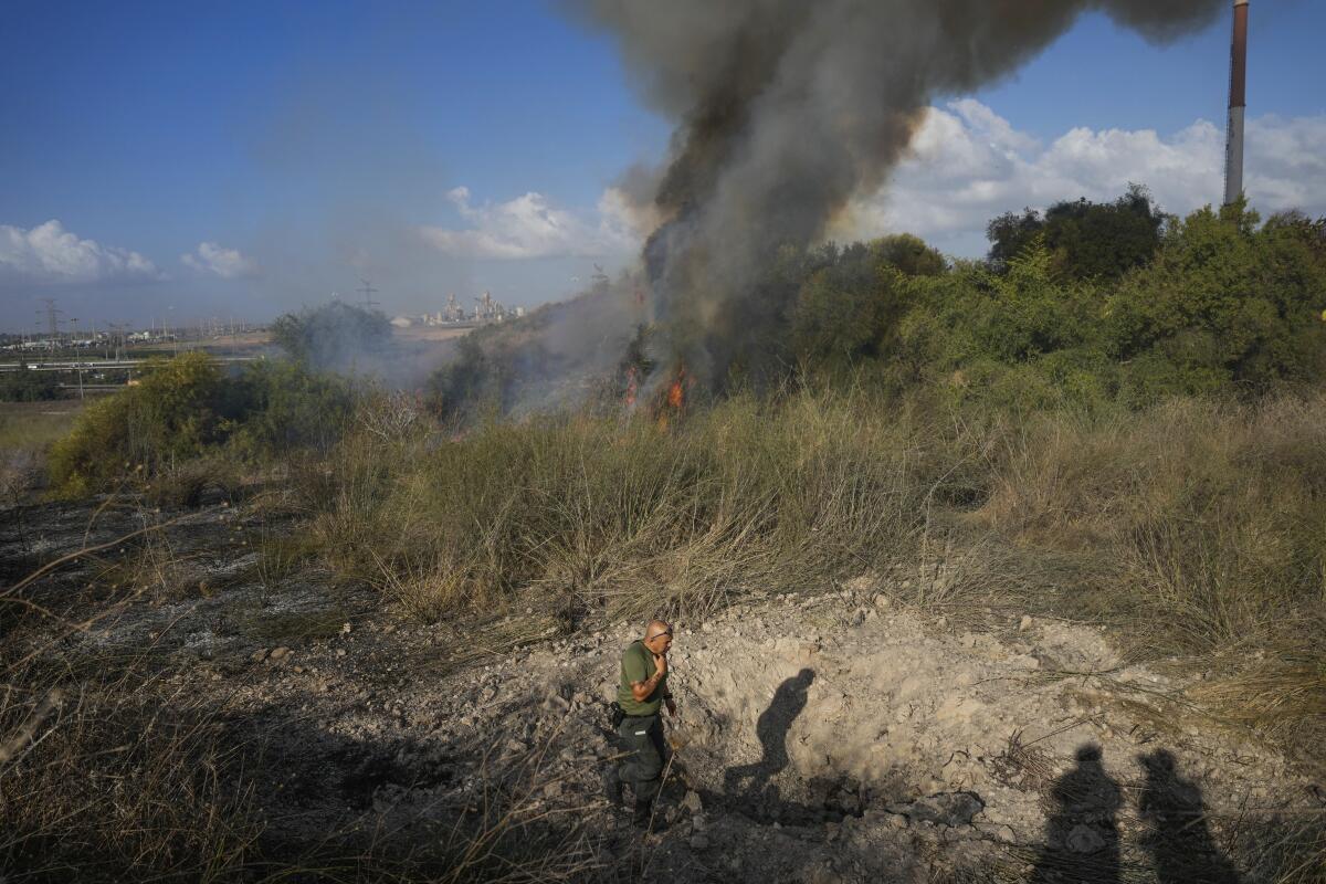 A police officer inspects the area around a fire in a field.