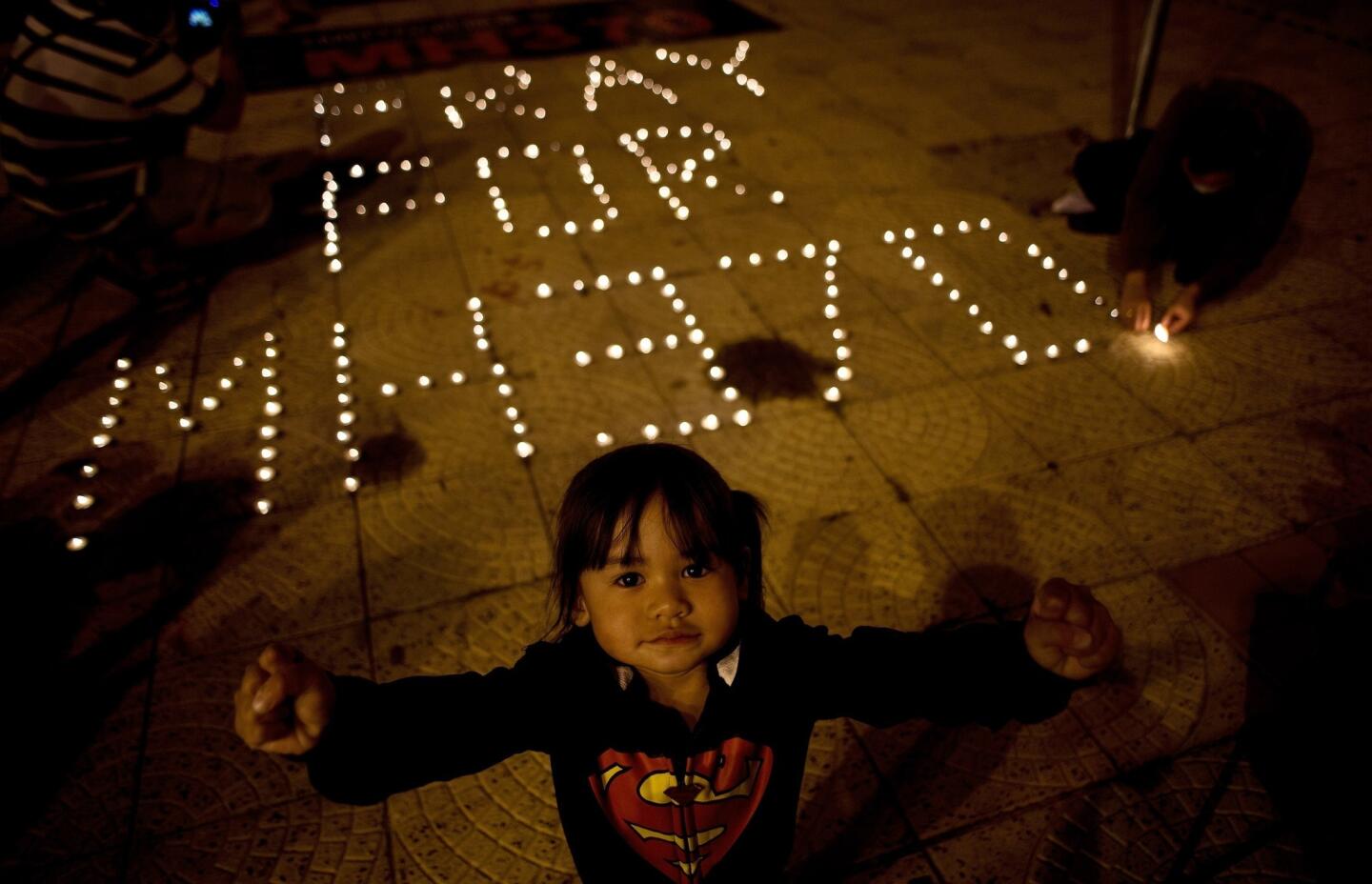 A Malaysian ethnic Chinese child reacts to the camera as others light candles during a vigil for missing Malaysia Airlines passengers at the Independence Square in Kuala Lumpur on March 10, 2014.