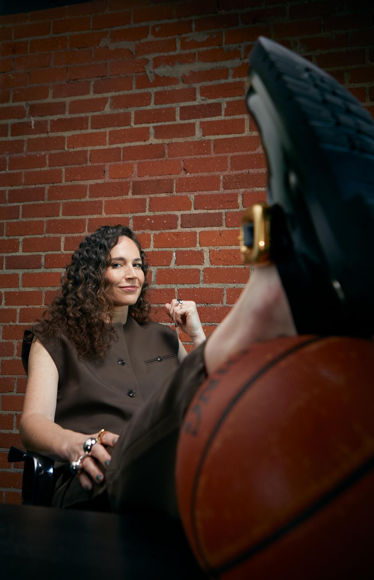 Sue Bird sits with her leg propped on a basketball.