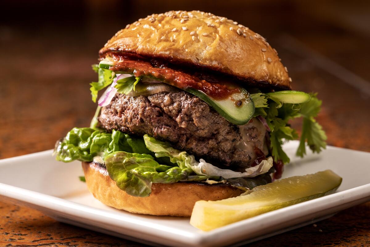  A piled-high hamburger, with a pickle spear.