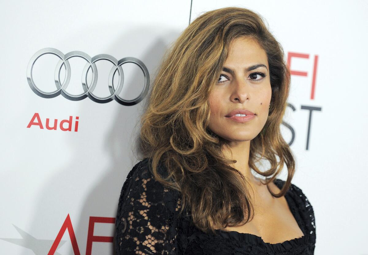 Eva Mendes wears a black lace dress and looks off to the side. 