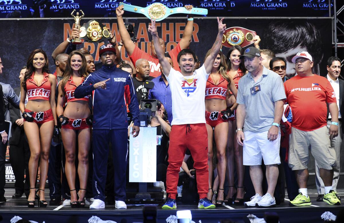 Floyd Mayweather Jr., left, and Manny Pacquiao strike different poses as they pose following their official weigh-in Friday at the MGM Grand Garden Arena before their welterweight title unification bout on Saturday.