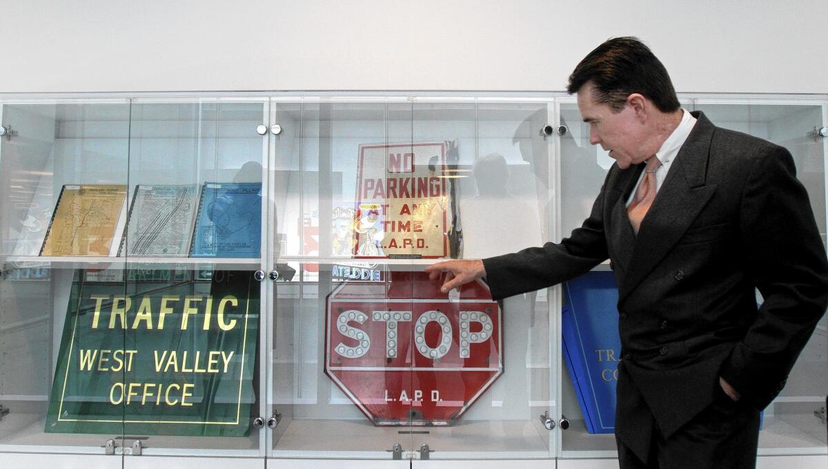 John Fisher, who retired two years ago after 39 years as a city Department of Transportation engineer and assistant general manager, shows vintage street signs at the Caltrans building in downtown Los Angeles. He amassed a collection of the designs and donated them for display.
