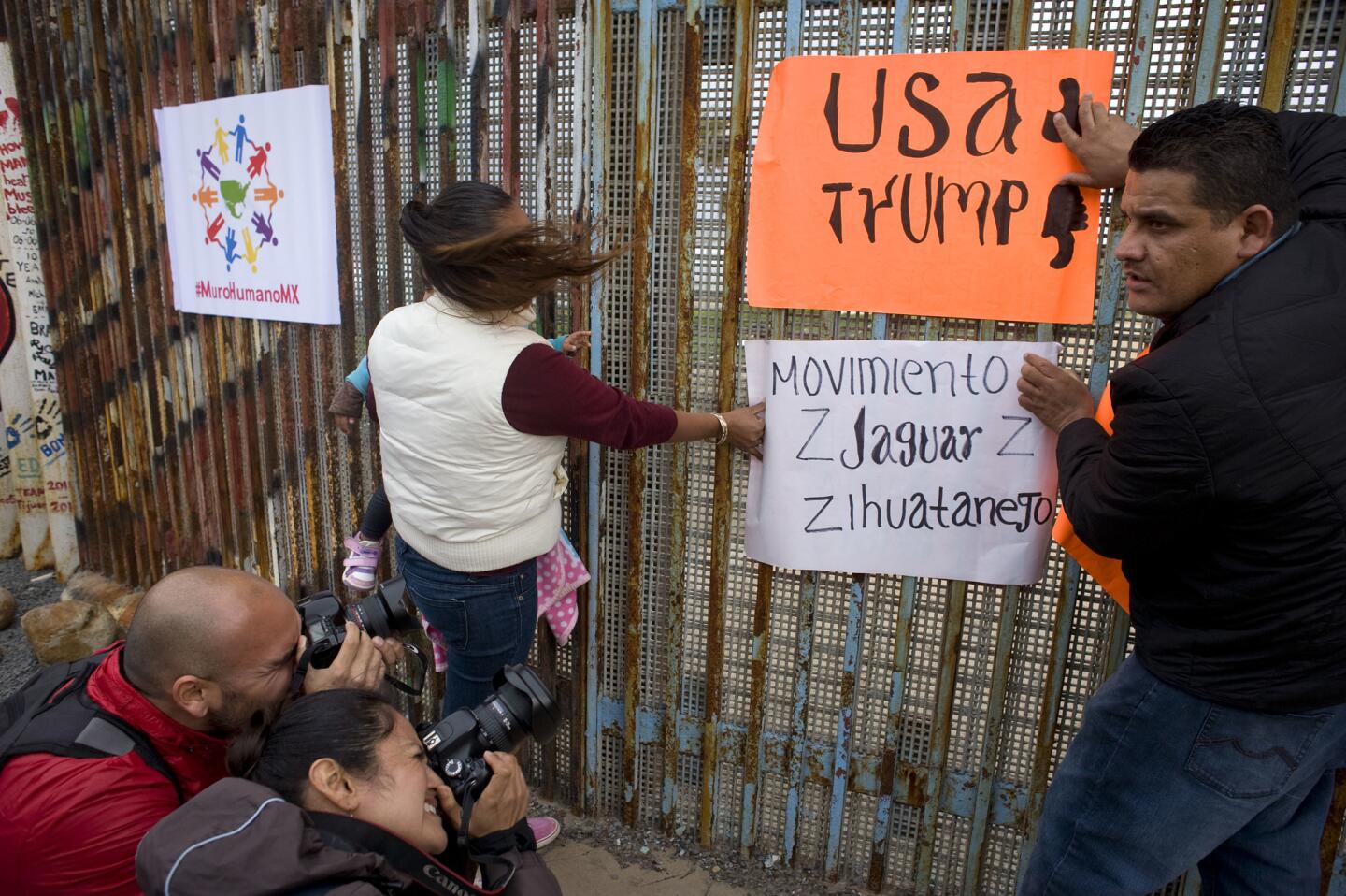 Un grupo de personas protesta junto a la cerca que marca el límite de la frontera de México con EEUU, en Tijuana. Trump ha prometido hacer que México pague el muro que construirá, algo que las autoridades mexicanas dicen que no harán.
