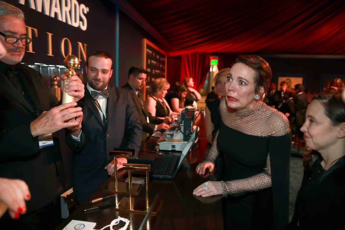 Olivia Colman ("The Favourite") eyes her Golden Globe shortly after getting it engraved.