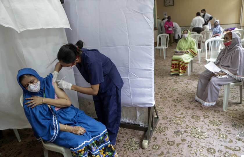 A woman gets inoculated against COVID-19 as others wait their turn in Mumbai, India
