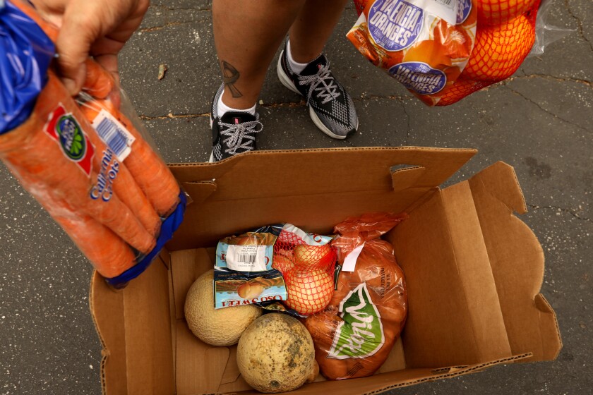 Yanira C. Ruiz, 50, looks over her box of produce she received at a food giveaway.