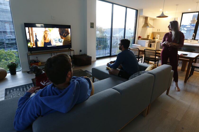 LOS ANGELES, CALIF. - MAR. 28, 2020. Colin Huitfeldt, 25, Jake Viramontez-Smith, 28, and Julia O. Test, 34, watch television in their shared-living apartment building in Venice. (Luis Sinco/Los Angeles Times)