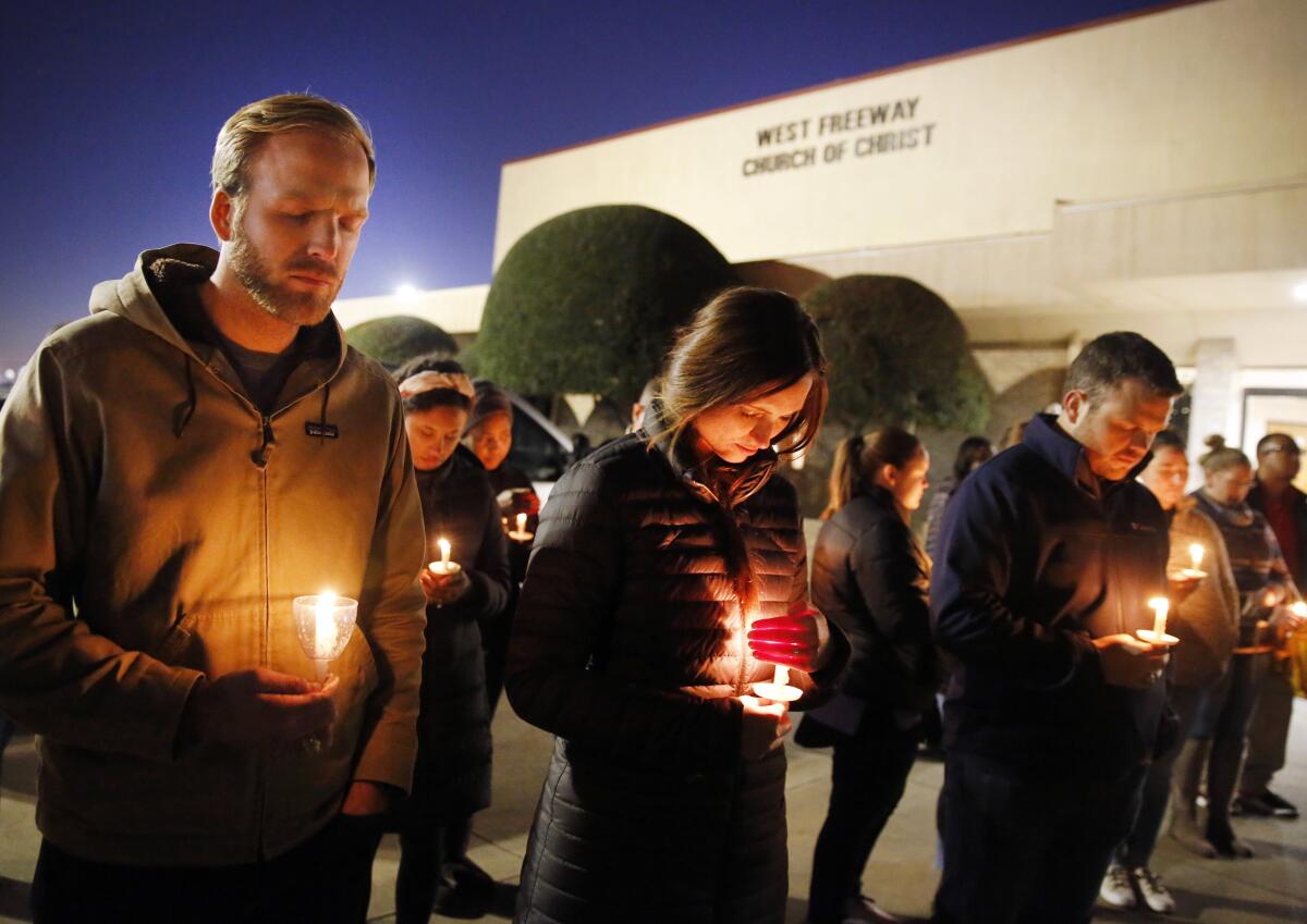 Matt Pacholczyk, left, and his wife, Faith, stand outside West Freeway Church of Christ for a candlelight vigil in White Settlement, Texas, on Monday.