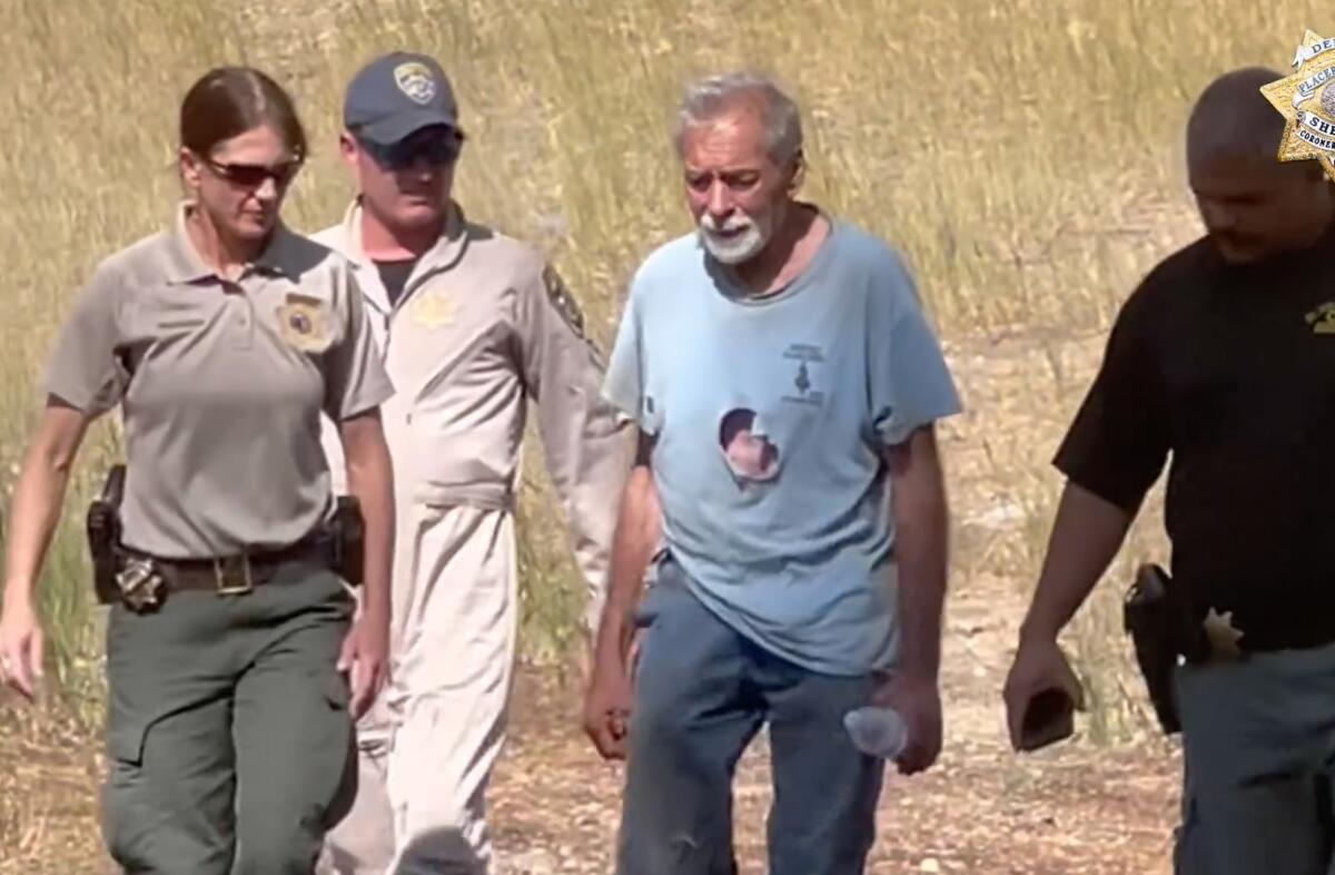 Warren Elliott, in a torn shirt, walks with authorities.