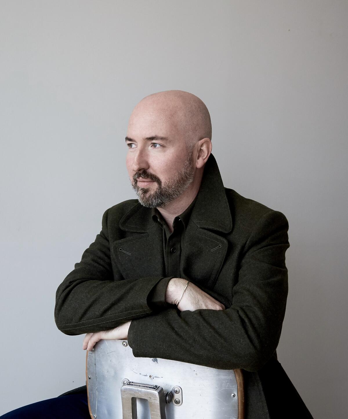 Author Douglas Stuart, seated backward on a chair.