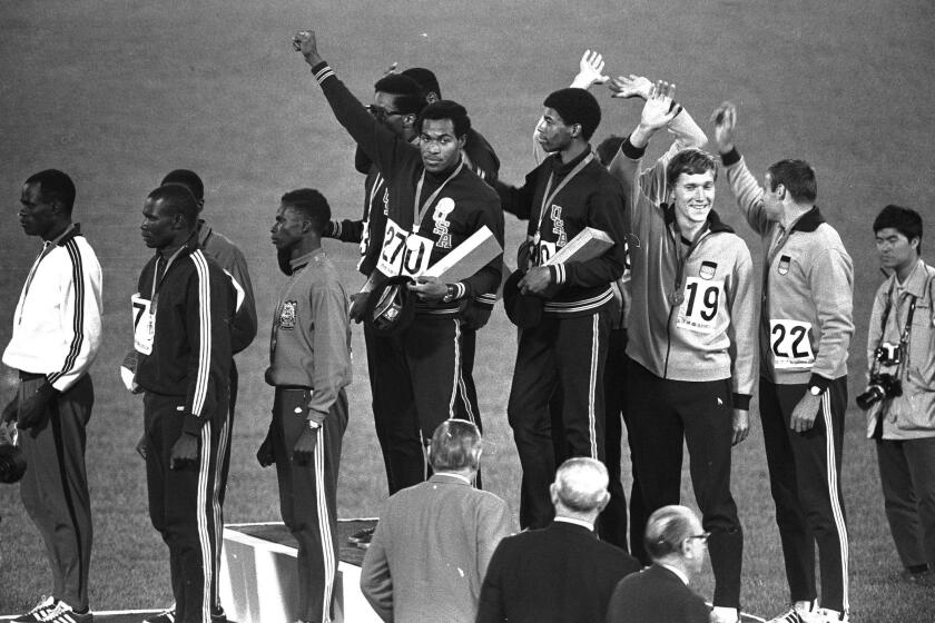 FILE - Lee Evans, a member of the United States 4X400-meter relay team, holds up a clenched fist after receiving his gold medal during medal presentations at the Mexico City Games in Mexico City, in this Oct. 21, 1968, file photo. Lee Evans, the record-setting sprinter who wore a black beret in a sign of protest at the 1968 Olympics, died Wednesday, May 19, 2021. He was 74. USA Track and Field confirmed Evans' death. The San Jose Mercury News reported that Evans' family had started a fundraiser with hopes of bringing him back to the U.S. from Nigeria, where he coached track, to receive medical care after he suffered a stroke last week. (AP Photo/FIle)