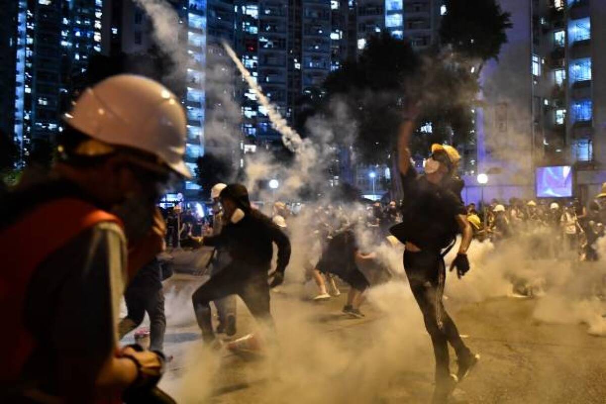 Protesters throw back tear gas canisters fired by the police in Wong Tai Sin during a general strike in Hong Kong on Monday as simultaneous rallies were held across seven districts.