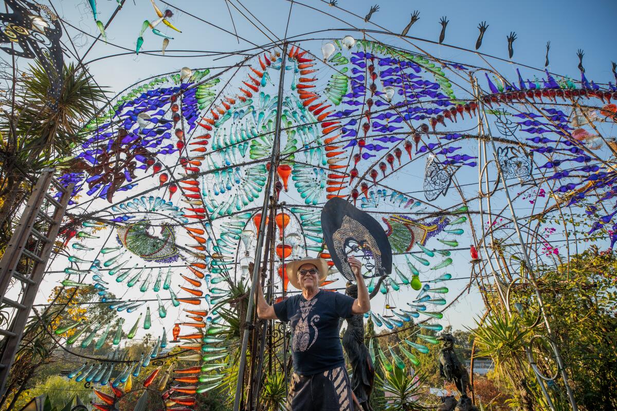  Randy King Lawrence standing in front of a massive metal and glass sculpture in his yard.