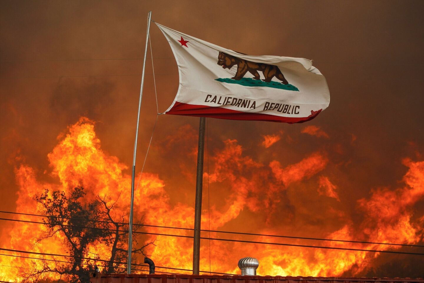 With flames nearby, the state flag flies next to a home on Highway 94 south of Potrero.