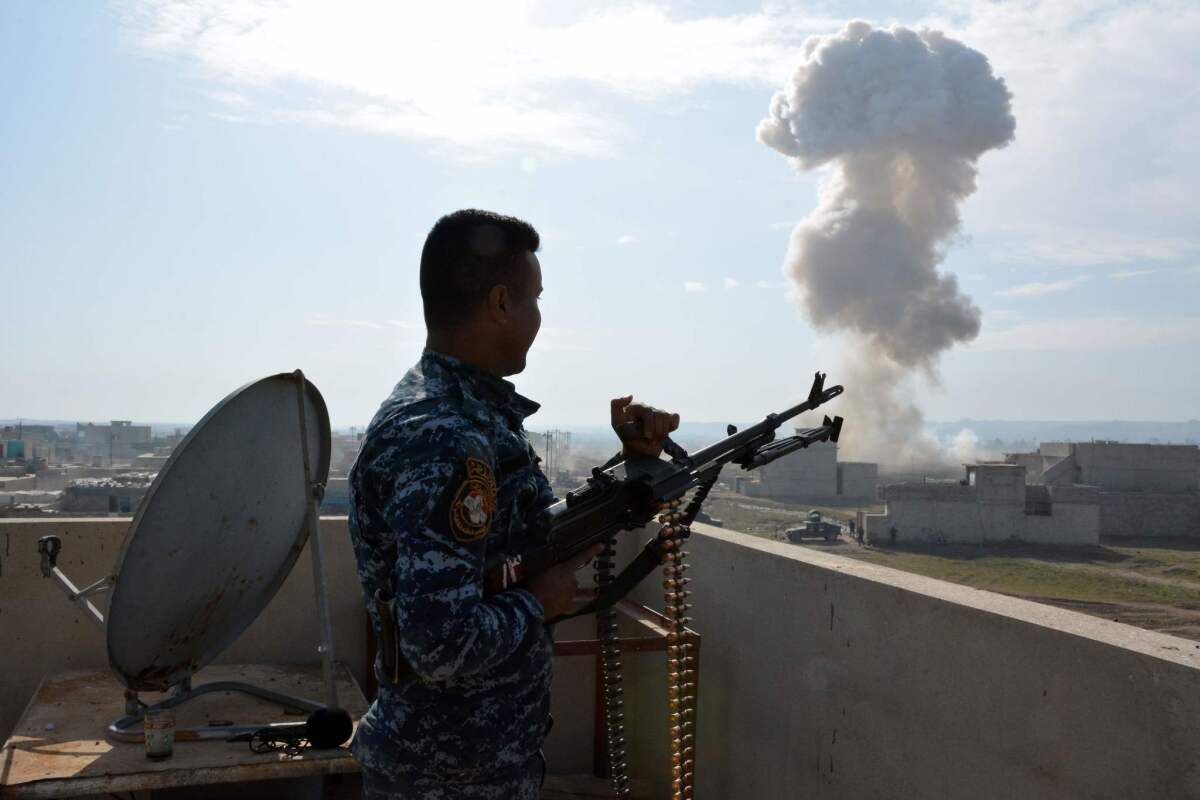 A member of Iraqi security forces watches smoke billow up after his comrades detonated a booby-trapped car left behind by Islamic State fighters in Mosul's southern Sumer neighborhood during operations to retake the city from IS.
