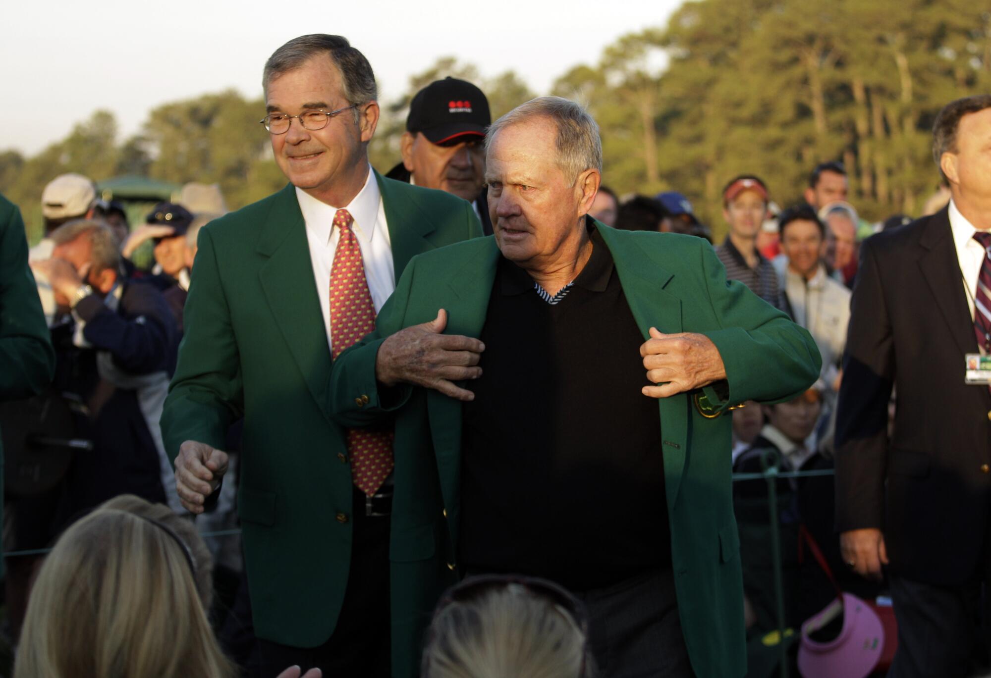 Jack Nicklaus, right, puts on his Masters green jacket in 2011 as Augusta National and Masters chairman Billy Payne watches.