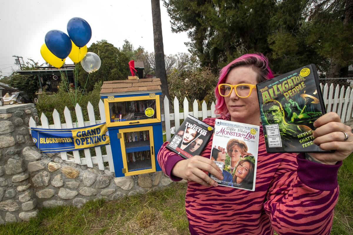 Alyssa Kollgaard stands next to a kiosk decked out to look like a Blockbuster store.