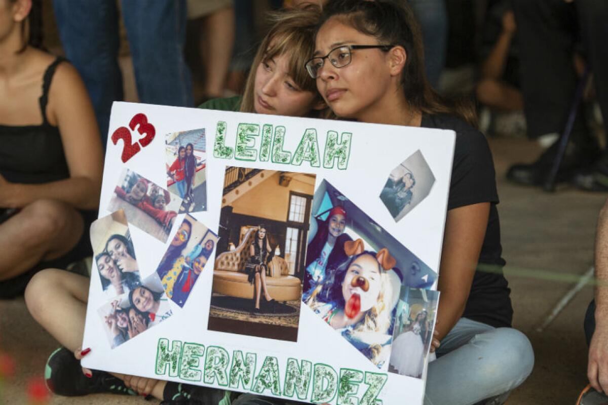 Two girls hold a sign in memory of a victim of the West Texas mass shooting