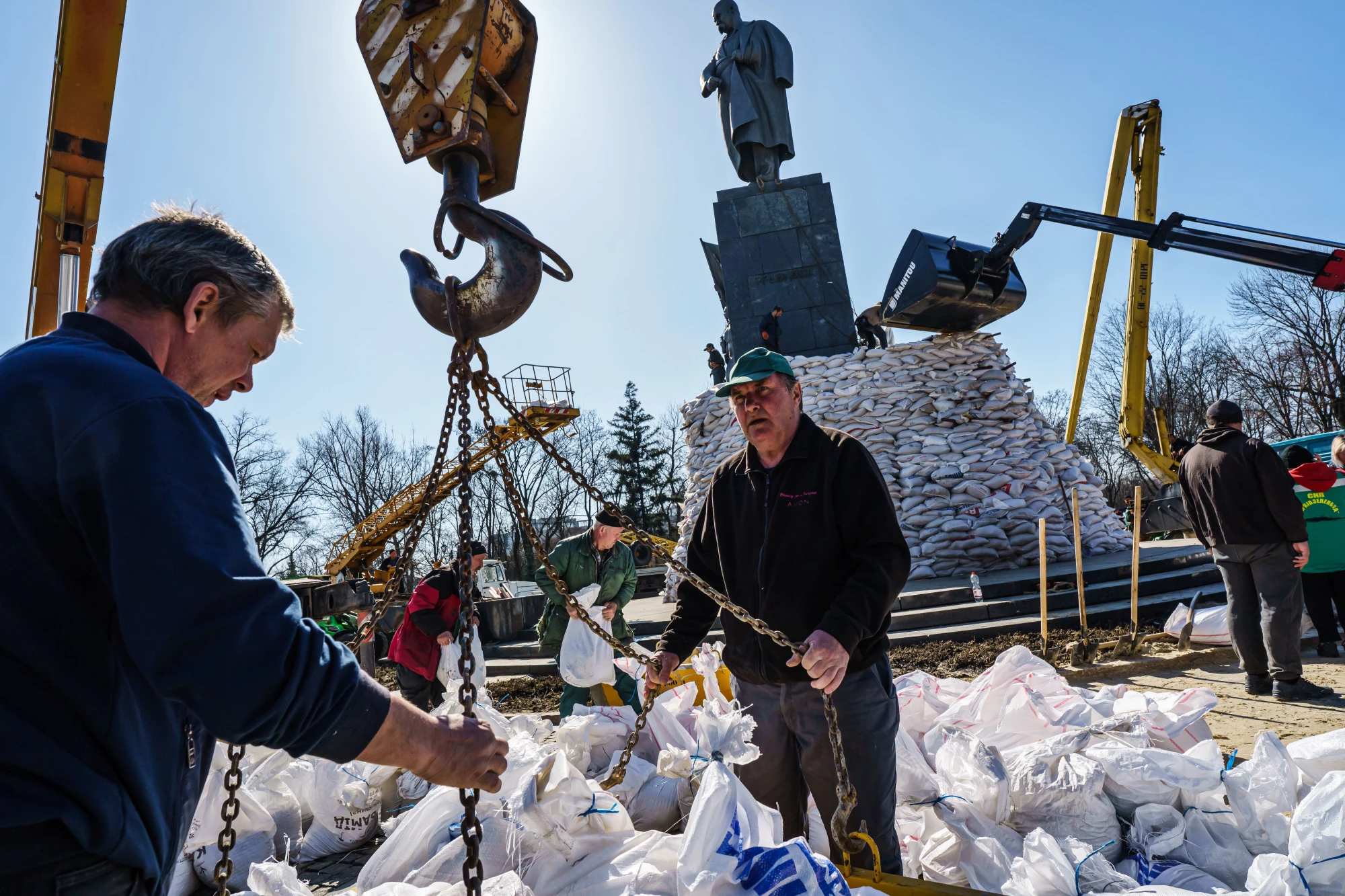 Dozens of volunteers pack sandbags and stack them around the Taras Shevchenko Monument in Kharkiv.