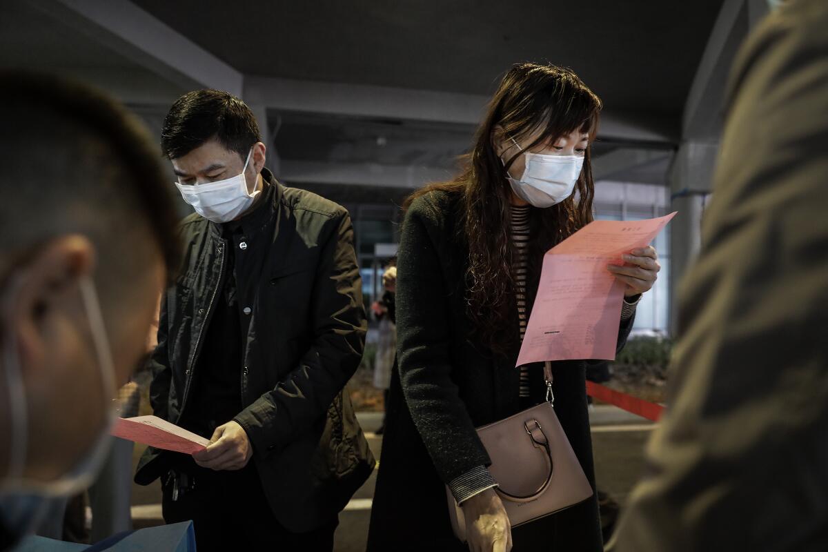 The staff member from a company communicates with the job applicant at an on-site job fair on Tuesday in Wuhan, China. The job fair had strict epidemic prevention measures.