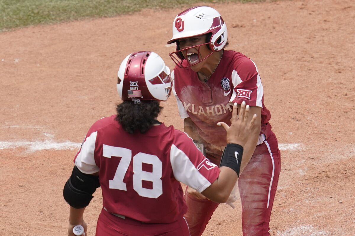 Oklahoma's Rylie Boone, right, celebrates with teammate Jocelyn Alo (78) after scoring on a hit by Tiara Jennings in the seventh inning of an NCAA Women's College World Series softball game Sunday, June 6, 2021, in Oklahoma City. (AP Photo/Sue Ogrocki)
