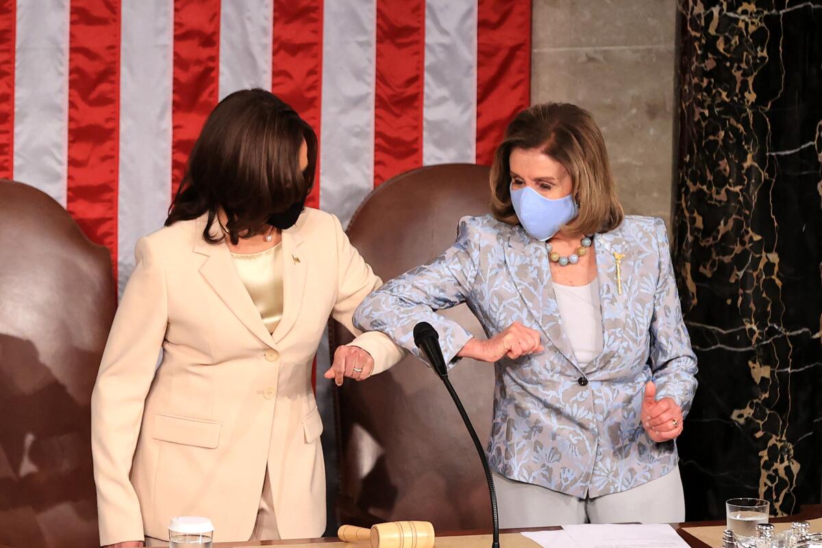 Vice President Kamala Harris, left, elbow bumps House Speaker Nancy Pelosi on the House dais. 