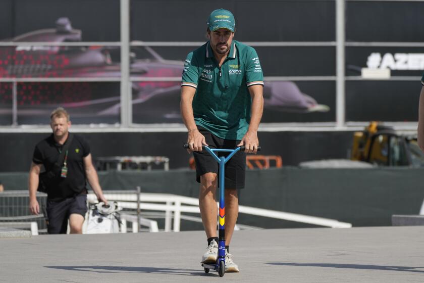 El piloto de Aston Martin Fernando Alonso conduce un scooter en el paddock del circuito de Bakú, el jueves 12 de septiembre de 2024. El circuito es la sede del Gran Premio de Azerbaiyán de la Fórmula Uno. (AP Foto/Sergei Grits)